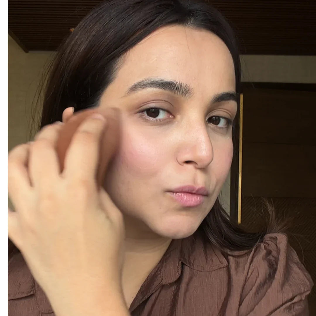Woman using a beauty sponge to blend makeup around her cheek and under-eye area.
